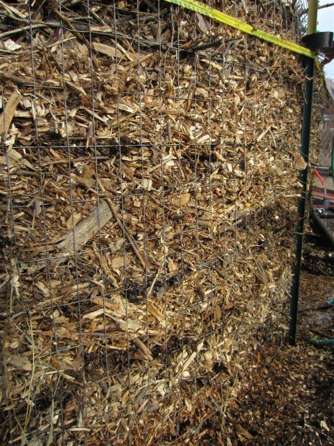 Layers of wood chips and manure in the compost pile