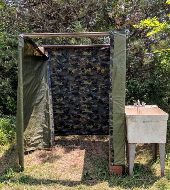 Low-cost outdoor shower house made with T-posts and a tarp